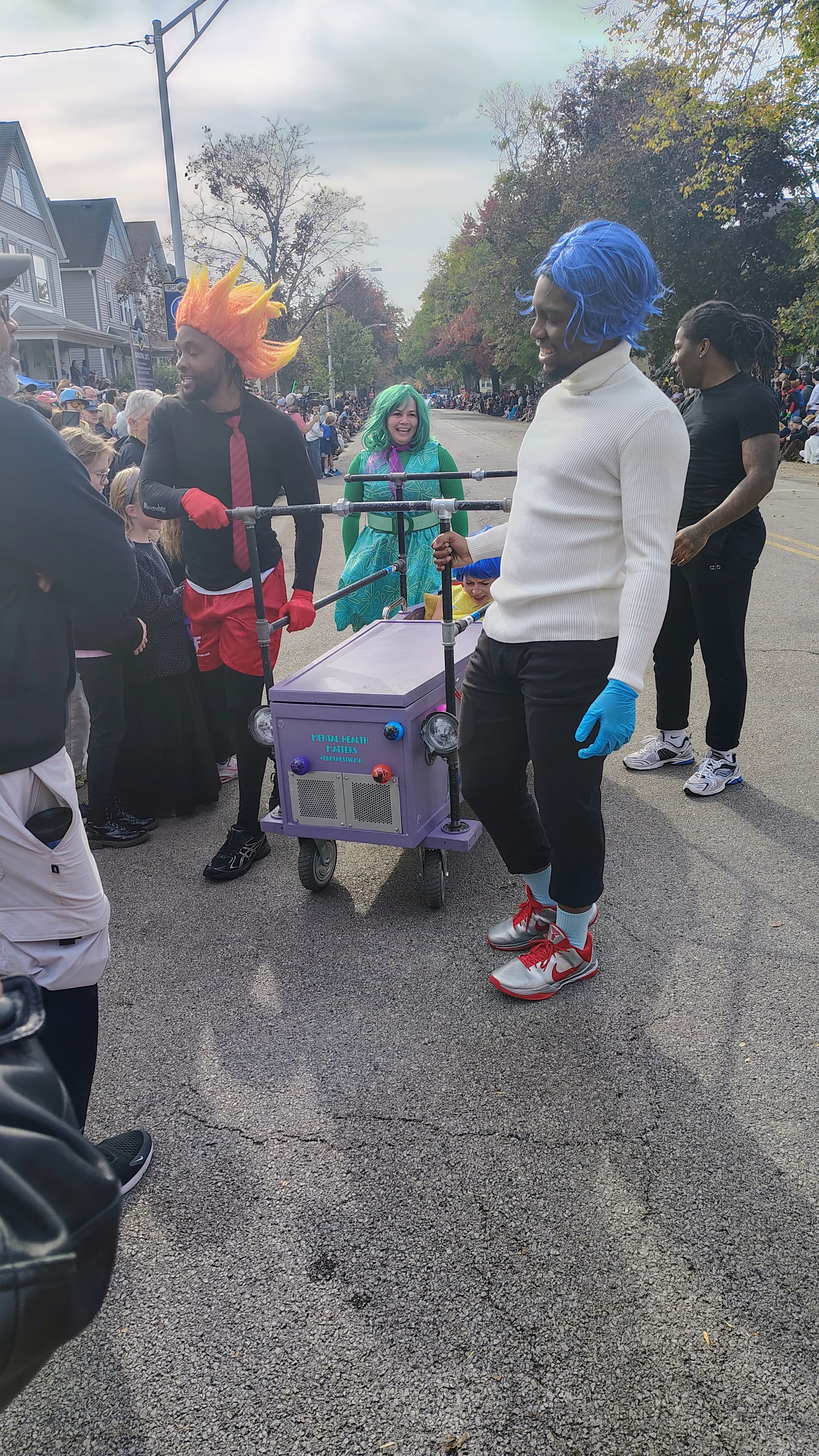 A crew dressed as Inside Out characters Joy, Envy, and Anger pushing a purple casket painted Mental Health Matters