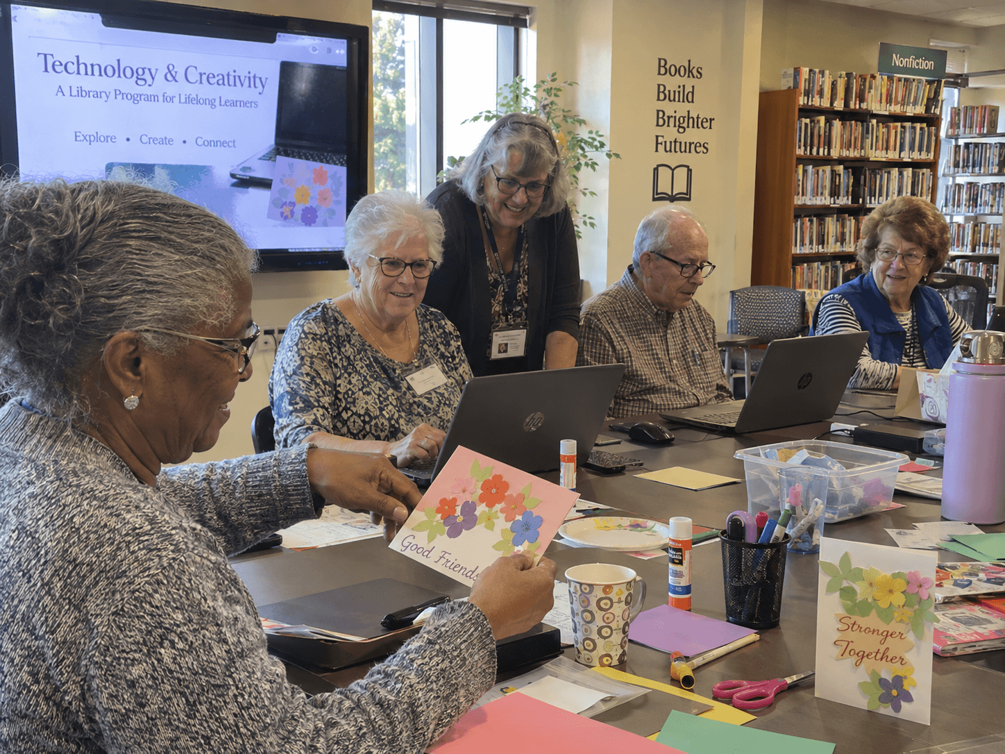 Older adults at a free library technology and creativity class, working on laptops and craft projects together