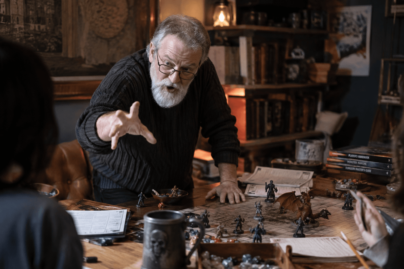 An older man with a gray beard leaning over a tabletop covered in dice, character sheets, and miniatures