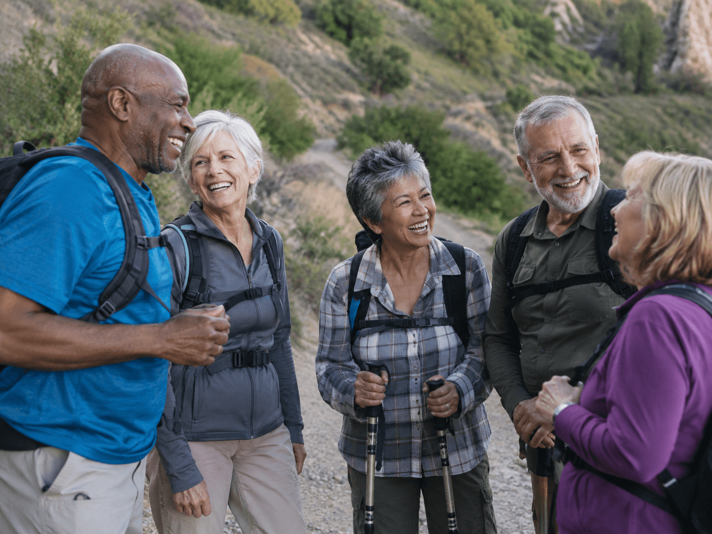 A group of seniors laughing together on a hiking trail, chatting like new friends